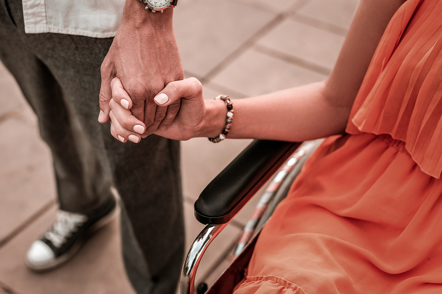 couple holding hands wheelchair